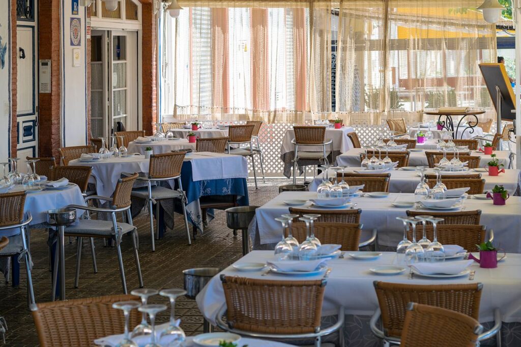 Charming outdoor dining area with neatly set tables in Sitges, Spain, bathed in natural light.
