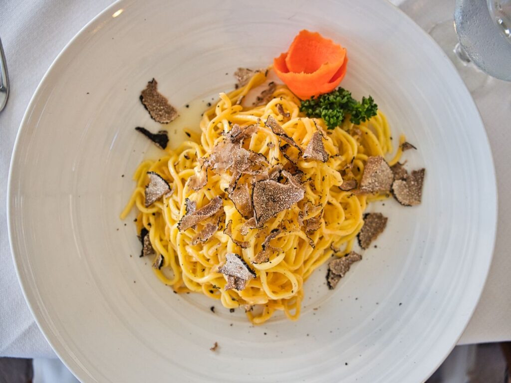 Delicious gourmet pasta served with truffle shavings and a vibrant garnish on a white plate.