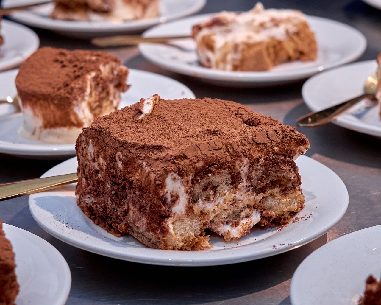 Close-up of a delectable tiramisu dessert on a white plate, dusted with cocoa powder.