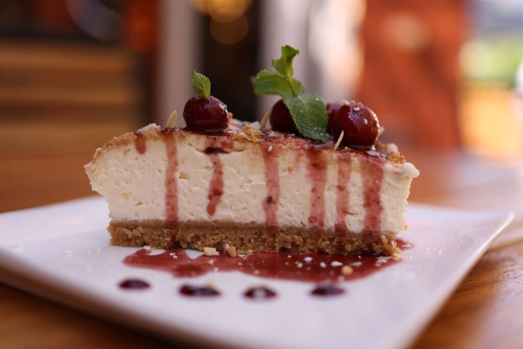 Close-up of a creamy cheesecake slice with cherry topping and mint garnish.