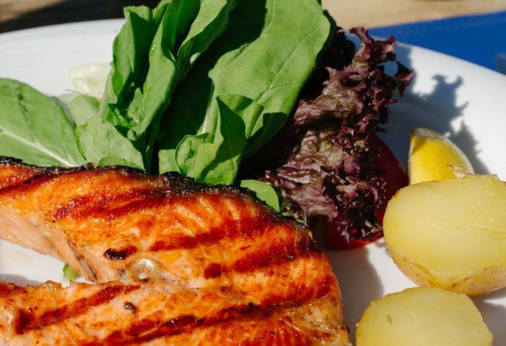 Delicious grilled salmon served with fresh greens and potatoes, perfect for a summer meal.